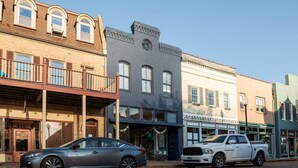 A row of historic buildings with a car and a truck parked in front. - Main Street 2BR Apartment with Garage and Deck (Saint Charles)