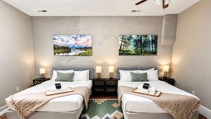 A double room with two beds, a brick wall, and two paintings. - Main Street 2BR Apartment with Garage and Deck (Saint Charles)