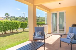 Ein Balkon mit zwei Stühlen und einem Tisch, eine Glastür sowie Blick auf eine grüne Landschaft.