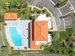 An aerial view of a hotel with a swimming pool, lounge chairs, and a playground.