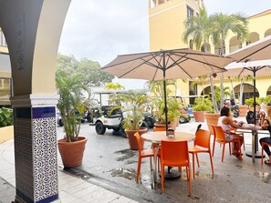 An outdoor cafe with tables and chairs, surrounded by potted plants and umbrellas. - Palmas del Mar Family Vacation Resort Spot!   (Palmas del Mar)