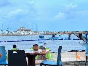 A seaside restaurant with outdoor seating, a view of the marina, and boats.