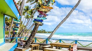 A beachside restaurant with a wooden deck, palm trees, and a view of the ocean. - Palmas del Mar Family Vacation Resort Spot!   (Palmas del Mar)
