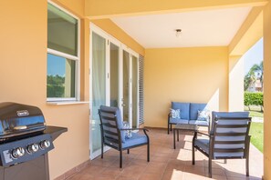 Eine Terrasss mit Grill, Stühlen und einer Sitzecke.