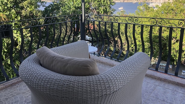 Un balcón con mobiliario de mimbre y vista a un lago y montañas.