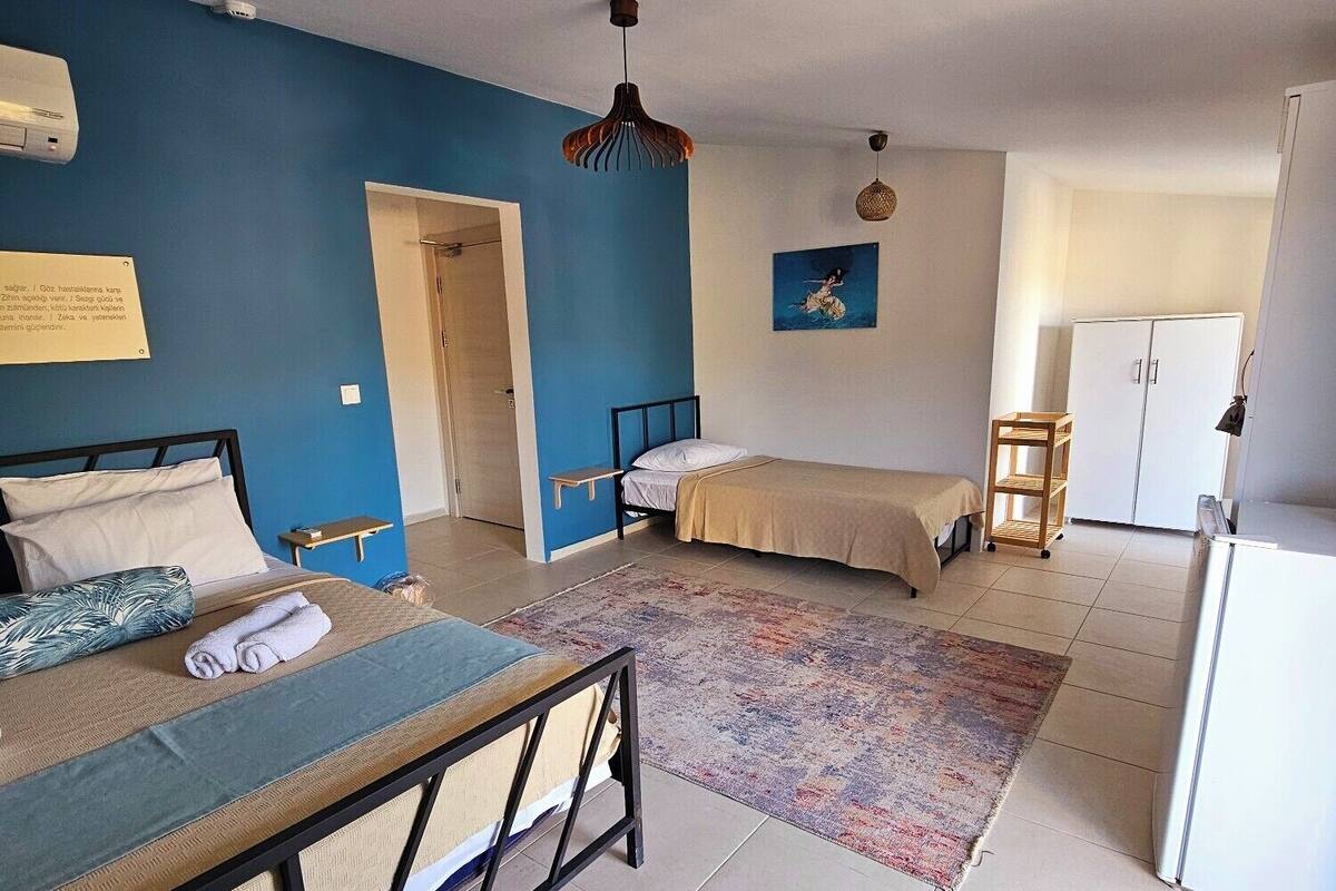 A room with a bed, a chair, a small table, a wardrobe, and a hanging light fixture.