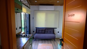 Un dormitorio compacto con cama, un pequeño kitchenette y una ventana.