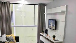 A modern living room with a sofa, a coffee table, and a TV mounted on the wall. - Ap Centro no Coração de BC - 500m do Mar (Balneário Camboriú)