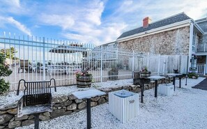 Enjoy a peaceful outdoor space with seating areas, tables, and a trash bin, surrounded by a stone wall and metal fence.