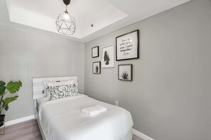 A bedroom with a bed, a geometric pendant light, and framed artwork on the wall. - 3BR Brickell | Free Parking | Skyline View (Miami)