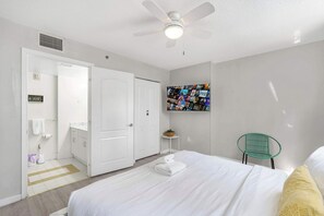 A hotel room with a bed, a ceiling fan, a wall-mounted photo collage, a green chair, and a small table with a basket. - 3BR Brickell | Free Parking | Skyline View (Miami)
