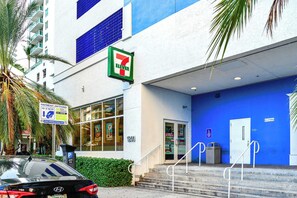 Ein 7-Eleven-Laden mit blauer Außenwand, einem Parkplatzschild und einer Treppe zum Eingang.