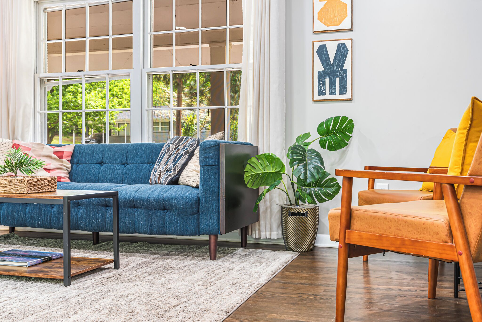 A living room with a blue sofa, a wooden chair, a coffee table, and a potted plant.