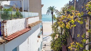 A coastal building with a view of the beach, a palm tree, and a staircase leading to a balcony. - Carreta Sea Views by Hello Homes Sitges (Sitges)