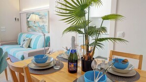 A dining table set with blue bowls, plates, and cutlery, a bottle of wine, and a potted plant. - Carreta Sea Views by Hello Homes Sitges (Sitges)