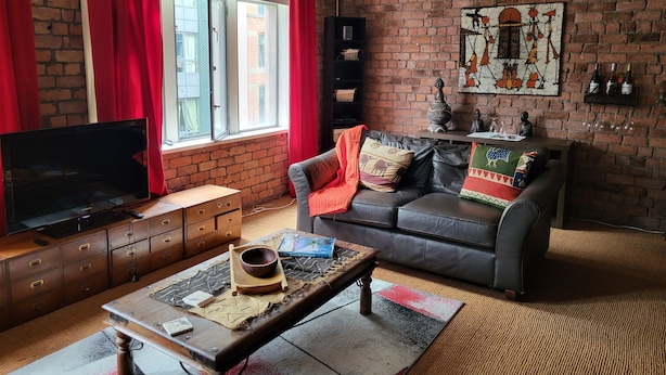 A living room with a brick wall, a television, a sofa, and a coffee table. - Captivating 2-bed Apartment in Liverpool (Liverpool)