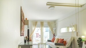 Habitación de hotel con cama, escritorio, silla, ventana con cortinas y balcón.