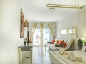 Ein Hotelzimmer mit Bett, Schreibtisch, Stuhl, einem Fenster mit Vorhängen und einem Balkon.