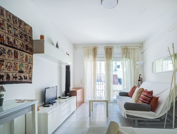 Una sala de estar moderna con un sofá, televisión y una pared decorada con obras de arte.