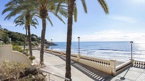A coastal promenade with palm trees, a tiled walkway, and a view of the sea. - Apartment by the Sea by Hello Homes Sitges (Sitges)