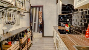 A kitchen with wooden cabinets, a countertop, and a variety of kitchen utensils and appliances. - Flamingo Apartment by Hello Homes Sitges (Sitges)