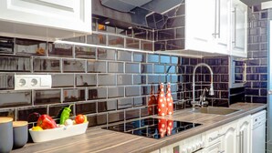 A modern kitchen with a black tiled backsplash, a wooden countertop, and white cabinetry. - Flamingo Apartment by Hello Homes Sitges (Sitges)