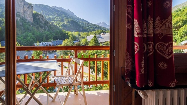 A balcony with a view of a mountainous landscape, a table, and a chair. - 2-room south-facing apartment with balcony and parking (Valloire)
