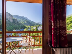 Un balcon donnant sur un paysage montagneux, avec une table et une chaise.