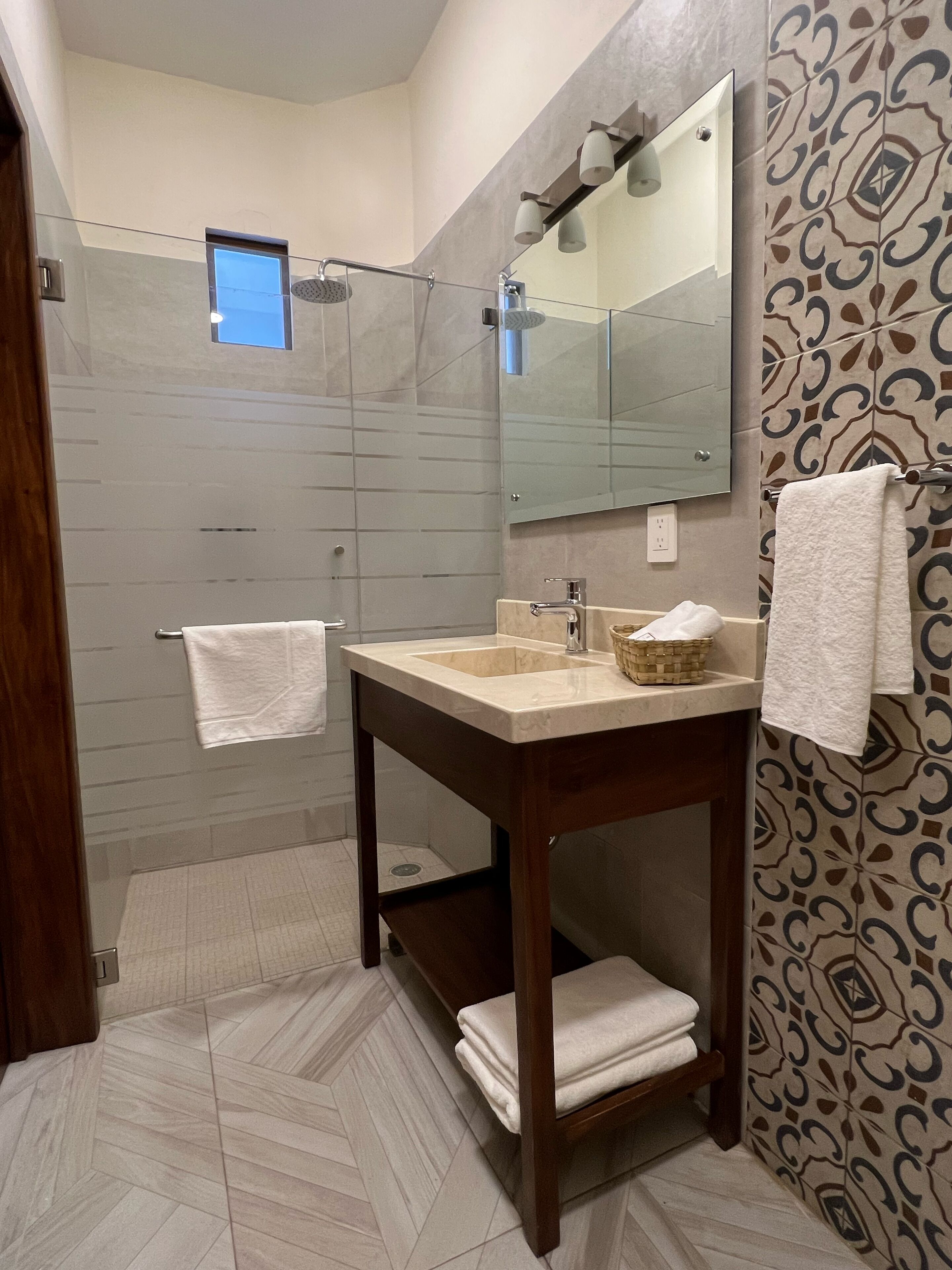 A modern bathroom with a shower, a sink, and a mirror.