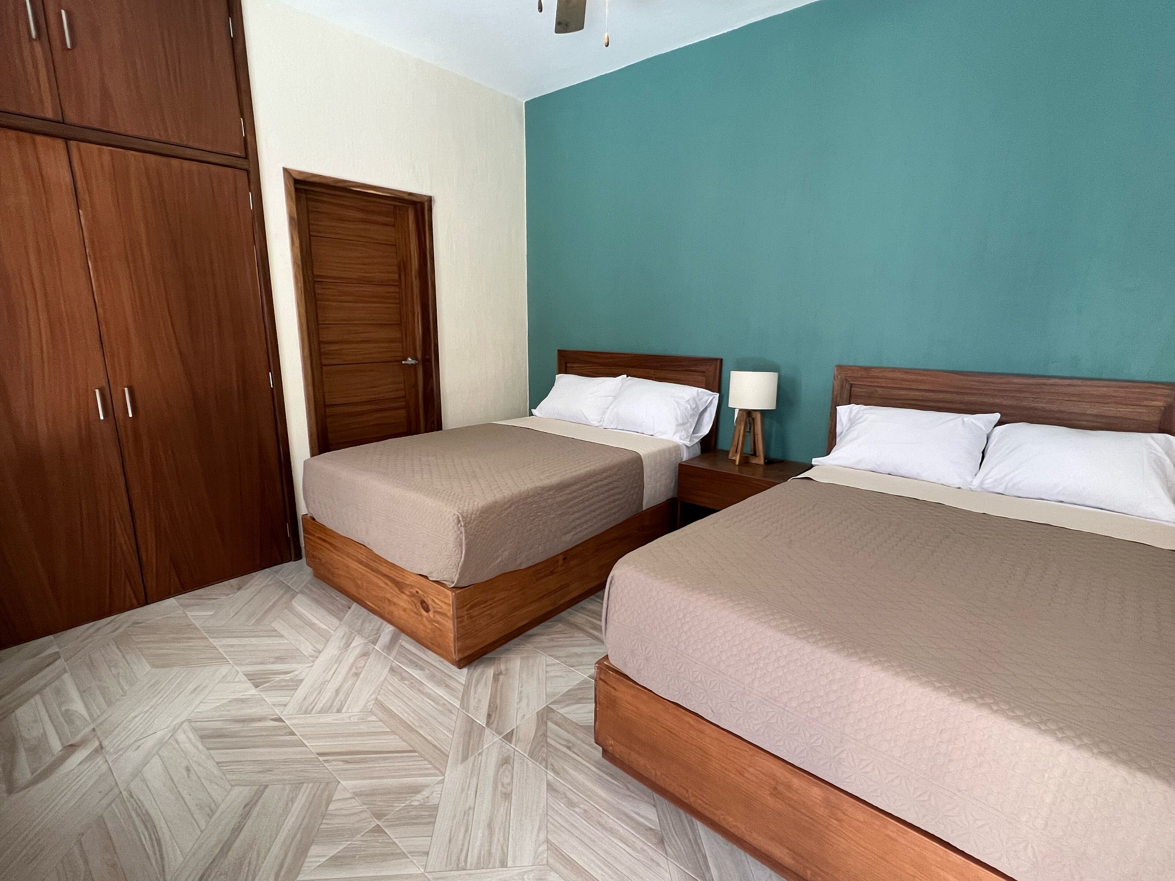 A hotel room with two beds, a wardrobe, and a door.