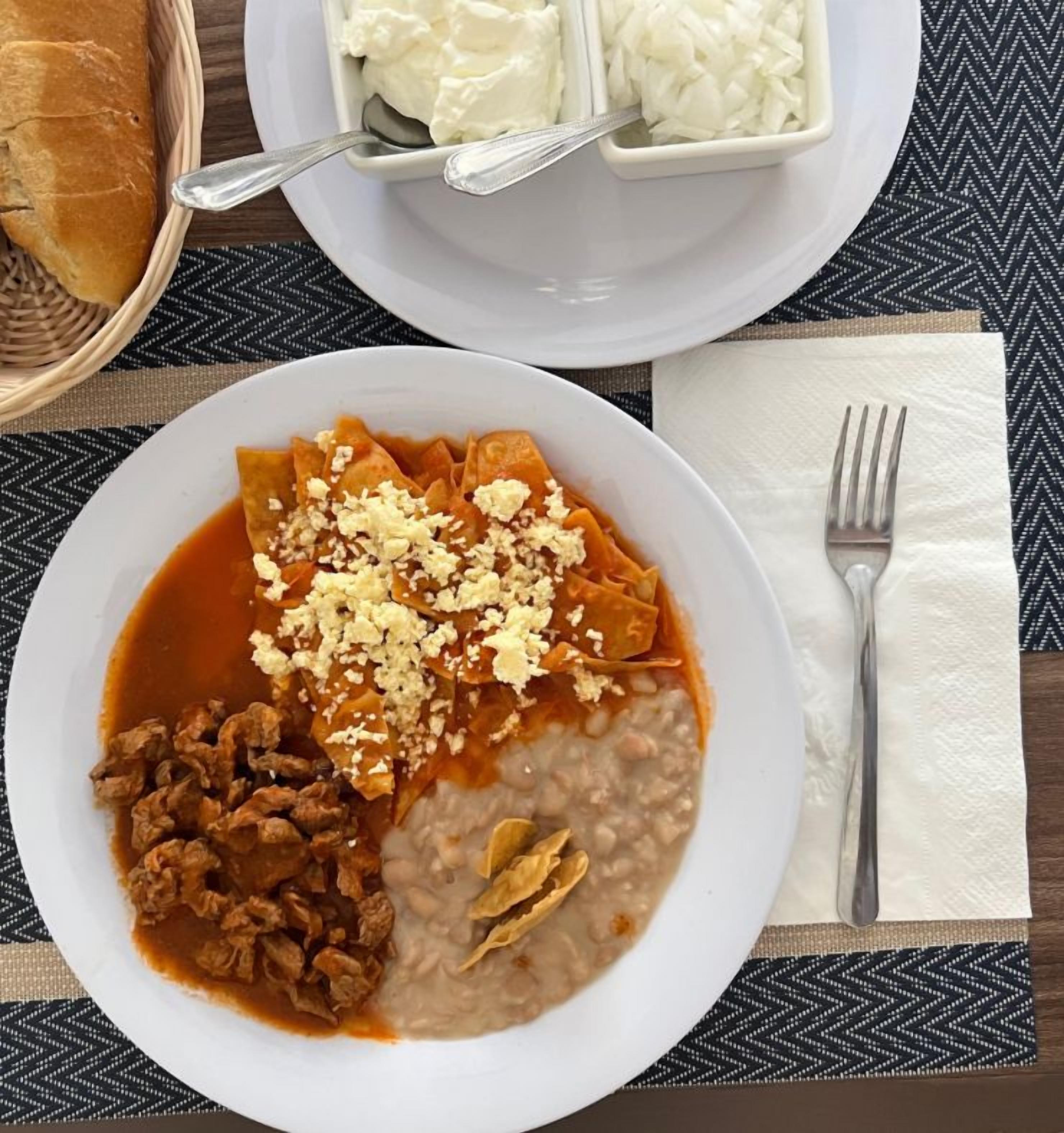 Ein Teller Essen mit Brot, eine Schale Sahne und ein Servietttuch mit einer Gabel.