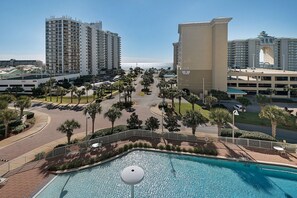 Un hotel con piscina, palmeras y vista al océano.