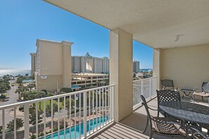 A balcony with a pool view, outdoor furniture, and a clear view of a hotel and ocean. -  Ariel Dunes l - Its Tannin' Time! - Fantastic Gulf Views! (Miramar Beach)
