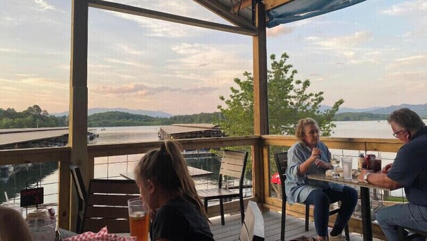 A covered outdoor seating area with a view of a lake and mountains. - Riverfront Cabin! Mountain Views, Pool, Hot Tub, Fishing, Tubing, Fire Pit, WIFI (Hiawassee)
