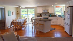 Una cocina amplia con armarios blancos, una isla central y un comedor con sillas y una mesa de madera.