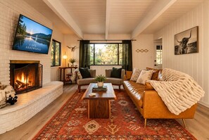 Una sala de estar acogedora con chimenea, asientos cómodos y un televisor montado en la pared.