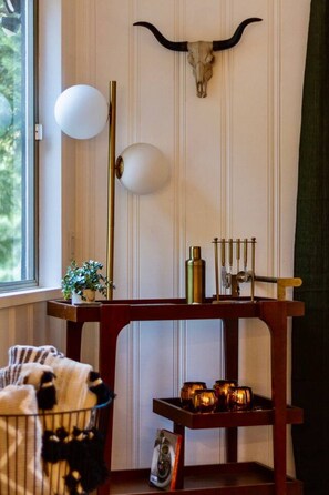 Una habitación con una mesa de madera, una lámpara de pared y un adorno en la pared.