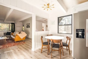 A modern interior with a dining area, a sofa, and a water dispenser. - Black Pine - 4BR Lake Arrowhead Cabin | Family & Pet-Friendly (Lake Arrowhead)