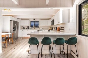Une cuisine moderne avec des meubles blancs, un îlot central et des tabourets de bar.