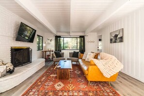 Un salon avec une cheminée, un canapé, une table basse et un tapis à motifs.