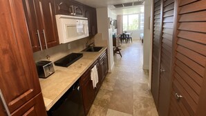 A kitchen with wooden cabinets, a microwave, a sink, and a dishwasher. - Beachfront condo in Miami! (Sunny Isles Beach)