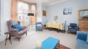 A living room with a sofa, armchairs, a dining table with chairs, a lamp, and a painting on the wall. - A West London Retreat (London)