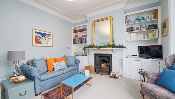 A living room with a blue sofa, a coffee table, a fireplace, a bookshelf, and a television. - A West London Retreat (London)