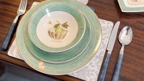 A table set with a green and white plate, a fork, knife, and spoon. - A West London Retreat (London)