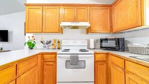 A kitchen with wooden cabinets, a white stove, a microwave, and a sink. - Peaceful retreat near the redwoods, ocean, and golf course! (Eureka)