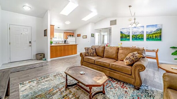 A spacious living room with a brown leather sofa, a wooden coffee table, and a colorful rug. - Peaceful retreat near the redwoods, ocean, and golf course! (Eureka)