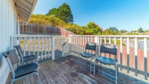 A wooden deck with four metal chairs and a table, overlooking a landscaped area with trees and a wooden fence. - Peaceful retreat near the redwoods, ocean, and golf course! (Eureka)
