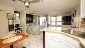 A modern kitchen with a granite countertop, stainless steel sink, and a ceiling fan.