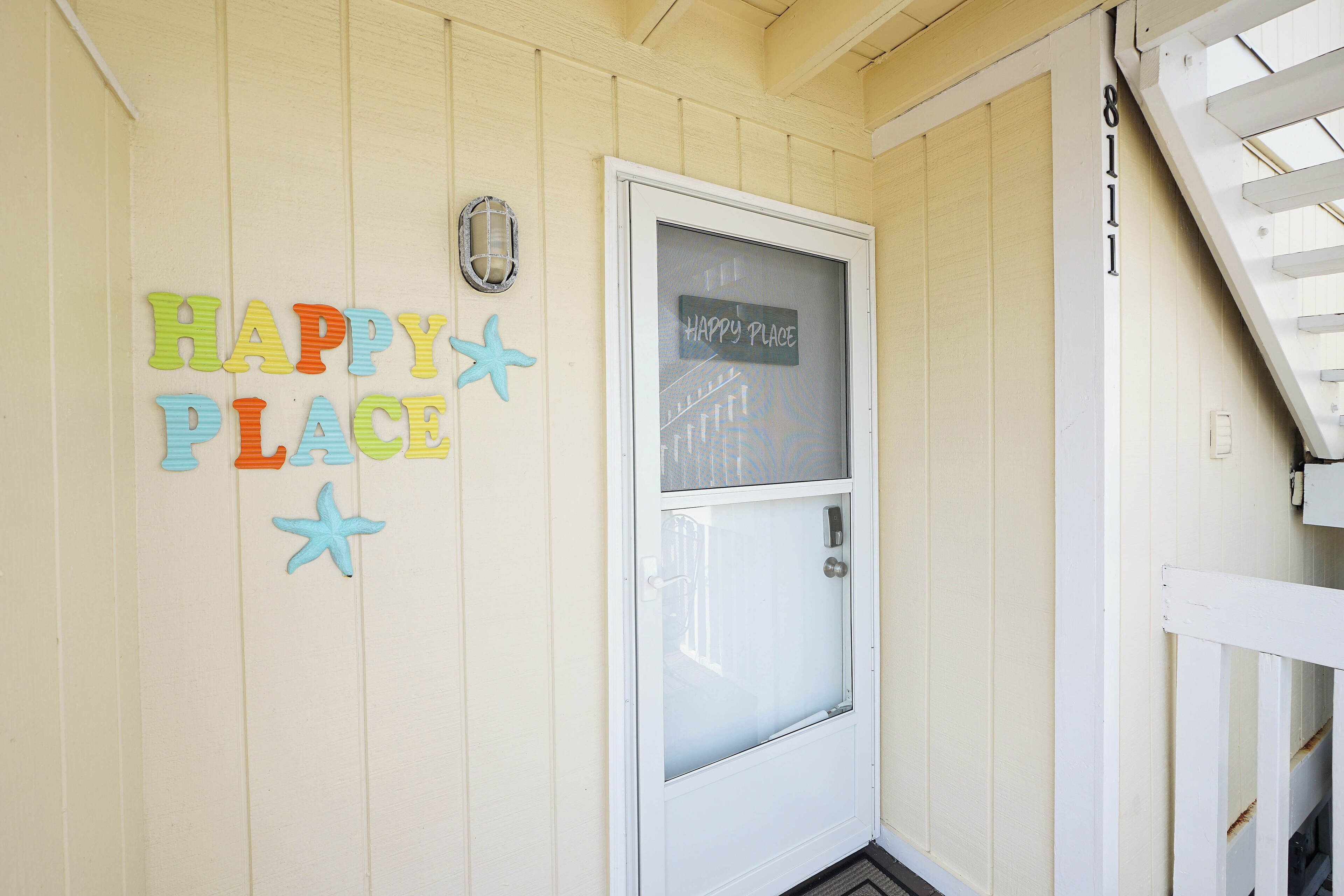 A white door with a frosted glass panel and a sign above it that reads "HAPPY PLACE".