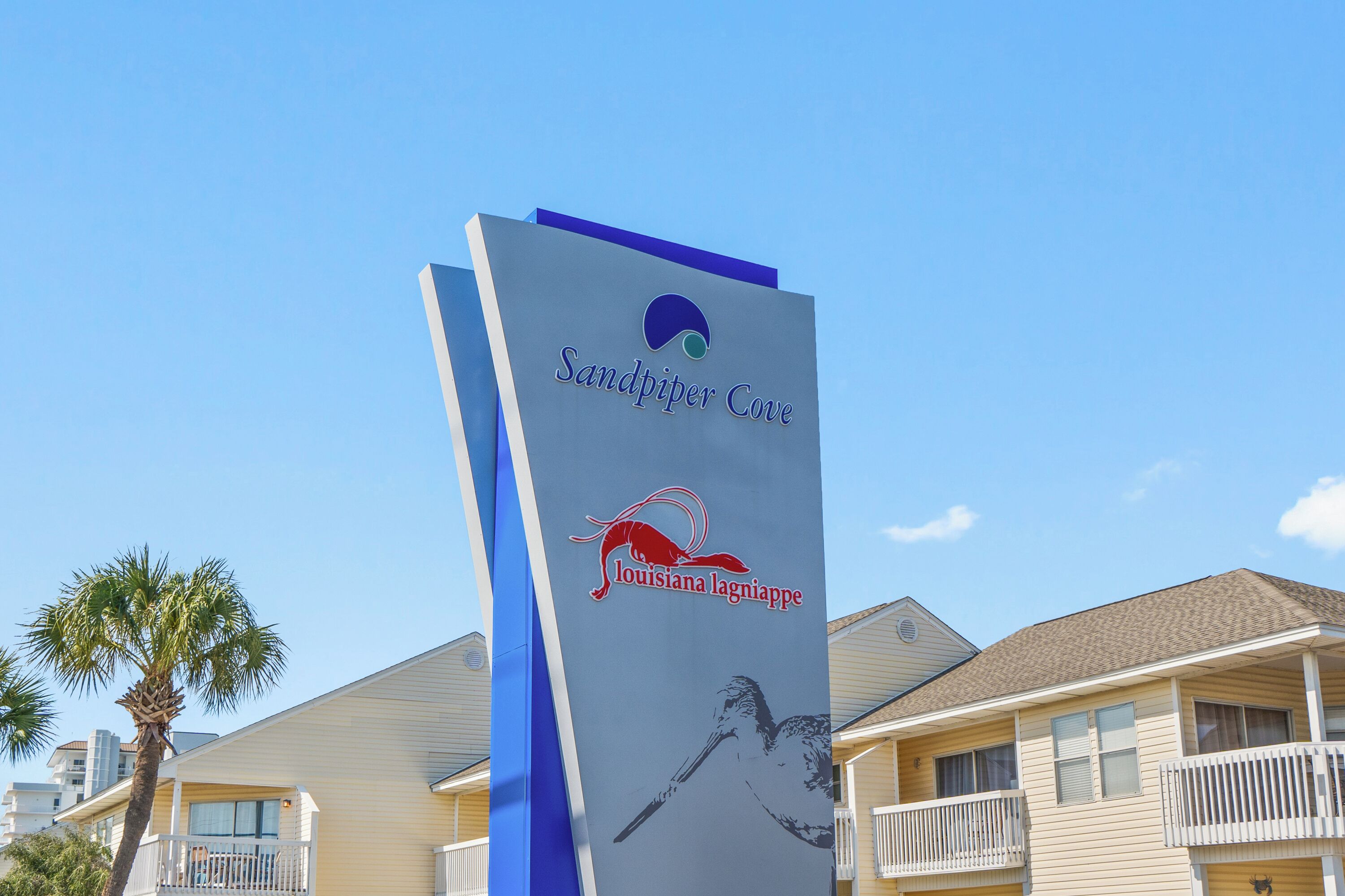 Schild für Sandpiper Cove mit einem Vogel-Logo und dem Text "Louisiana lagniappe".